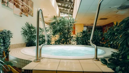 Ein entspannender Whirlpool umgeben von grünen Pflanzen. Die Atmosphäre ist ruhig und einladend.