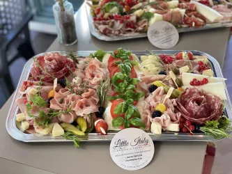 Eine ansprechende Platte mit verschiedenen Wurst- und Käsesorten, garniert mit frischen Kräutern und roten Beeren. Ideal für eine festliche Präsentation.
