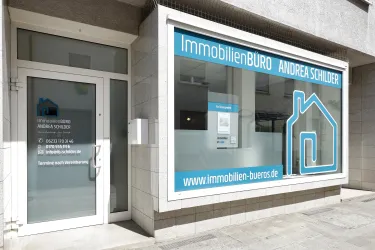 Ein Immobilienbüro mit einem modernen Schaufenster. Die Fenster sind klar und zeigen einen ansprechenden Schriftzug.