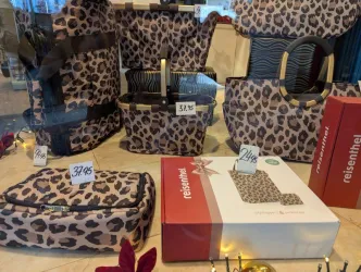 Eine Ansammlung von Taschen mit Leopardenmuster in verschiedenen Größen ist zu sehen. Einige Taschen haben Preisschilder, die auf unterschiedliche Preise hinweisen.