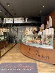 Ein modernes Eiscafé mit einer großen Glasvitrine, die eine Vielzahl von Eissorten zeigt. Der Innenraum ist stilvoll mit Holz und Spiegeln gestaltet.