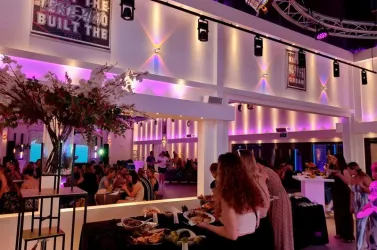 Eine elegante Veranstaltung in einem modernen Raum mit bunten Lichtern. Die Gäste genießen ein Buffet und unterhalten sich in geselliger Atmosphäre.