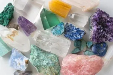 Eine Sammlung von bunten Mineralien und Kristallen in verschiedenen Formen und Farben. Die Steine sind aus verschiedenen Materialien, darunter Amethyst, Quarz und Malachit.