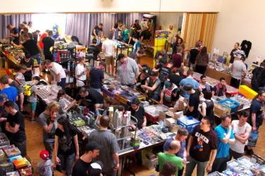 Eine lebhafte Messe mit vielen Menschen, die an Ständen mit Spielzeug und Sammlerstücken stöbern. Die Atmosphäre ist geschäftig und bunt.