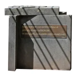 Ein Gedenkstein mit einer Metalltafel, die an die Ermordung der jüdischen Mitbürger erinnert. Die Struktur ist aus grauem Stein und steht im Freien.