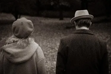 Ein Paar läuft in einem herbstlichen Park. Die Szene ist in sepia Farben gehalten, was eine nostalgische Stimmung erzeugt.
