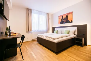 Ein gemütliches Schlafzimmer mit einem großen Bett und Holzboden. Neben dem Bett steht ein Tisch mit Snacks und Wein, sowie ein Fernseher an der Wand.