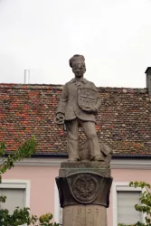 Figur auf einem Brunnen mit Schild und Brezel in der Hand