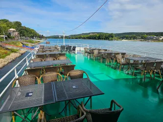 Das Sonnendeck eines Ausflugsschiffs auf dem Rhein mit Sitzmöbeln und Tischen