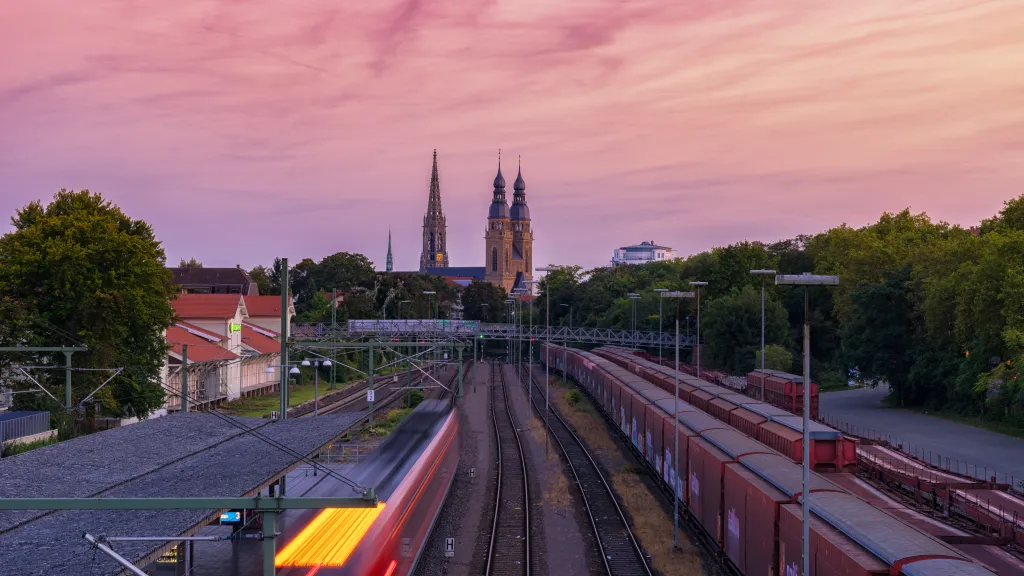 Bahnschienen und zwei Kirchen im Hintergrund bei Sonnenuntergang