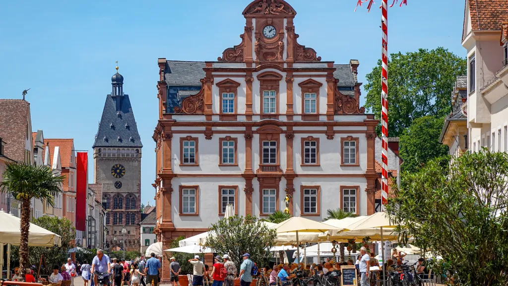 Belebte Innenstadt Speyers mit großem Gebäude, Stadttorturm und Außengastronomie