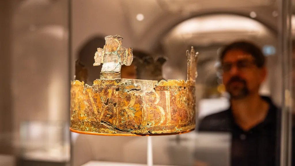 Mittelalterliche Krone in einer Glasvitrine, im Hintergrund steht ein Mann