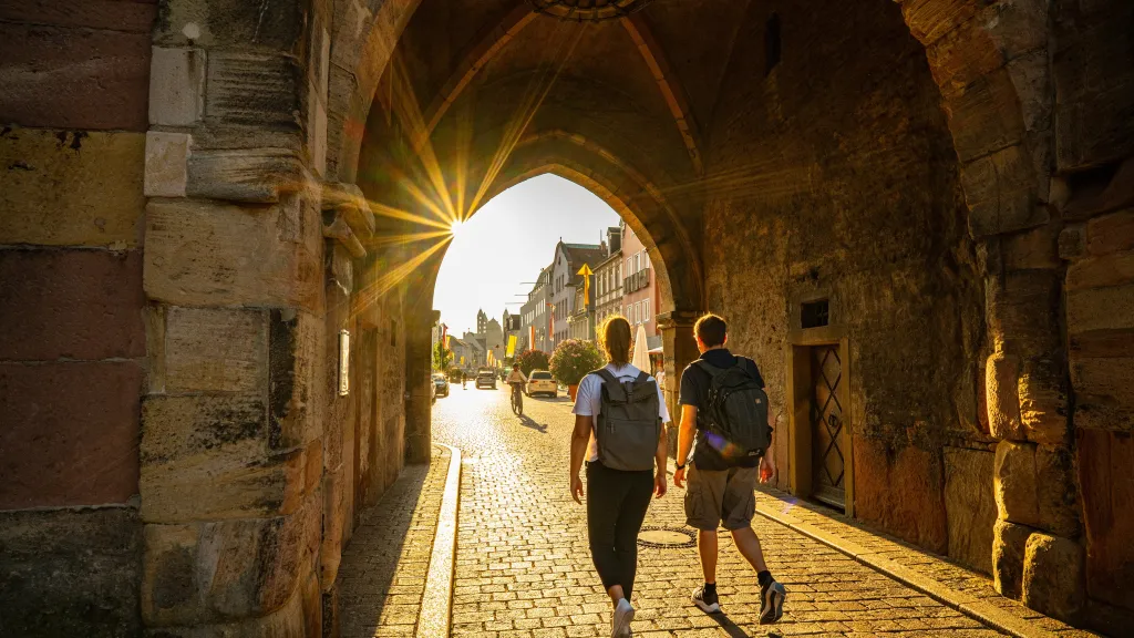 Zwei  Personen laufen durch ein Tor in die Innenstadt Speyers