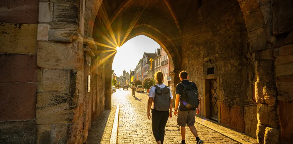 Zwei  Personen laufen durch ein Tor in die Innenstadt Speyers