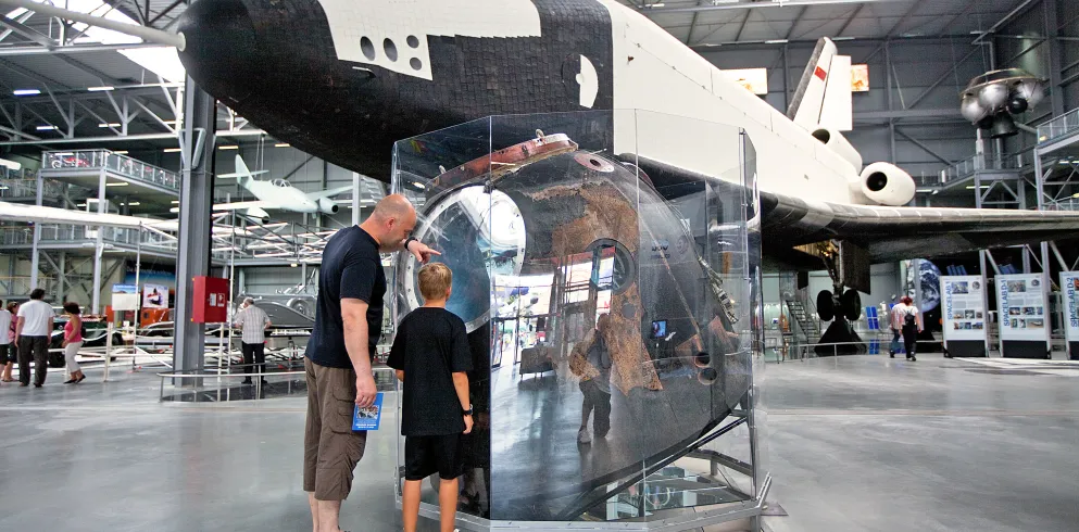Ein Mann und ein Junge stehen vor einem Museumsobjekt im Technik Museum Speyer