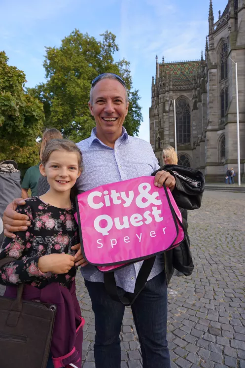 Ein Mann und ein Mädchen lächeln in die Kamera, in der Hand halten sie eine pinkfarbene Tasche