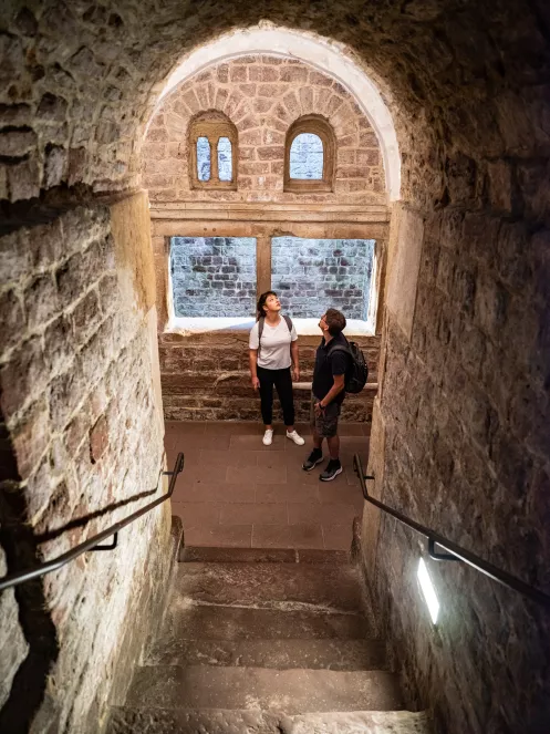 Zwei Personen stehen in einem Gemäuer am Fuße einer Treppe
