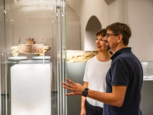 Sammelausstellung Kreuz und Krone im Historischen Museum der Pfalz Speyer (© Pfalz Touristik e.V., Sebastian Fachenbach) Zwei Personen stehen vor einer Glasvitrine hinter der eine Krone zu sehen ist