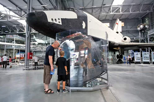 Ein Mann und ein Junge stehen vor einem Museumsobjekt im Technik Museum Speyer