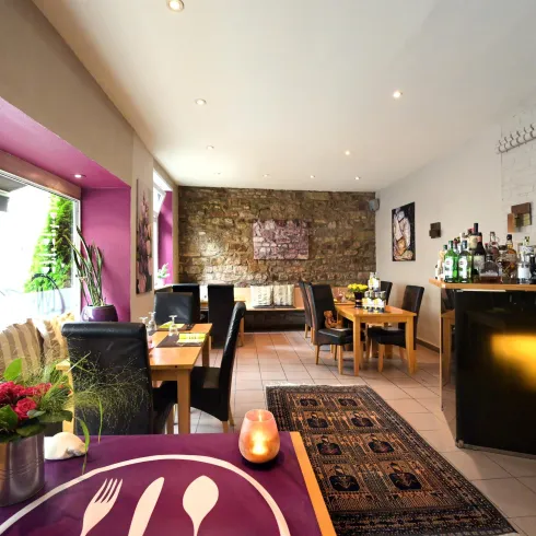 Ein modernes Restaurant mit Holz- und Steinelementen. Die Einrichtung ist stilvoll und einladend, mit einem funktionalen Barbereich.