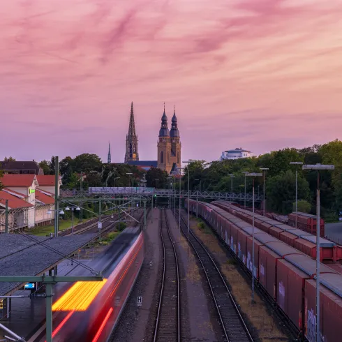 Bahnschienen und zwei Kirchen im Hintergrund bei Sonnenuntergang