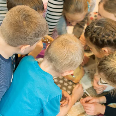 Viele Kinder stecken die Köpfe über einem Tisch zusammen 