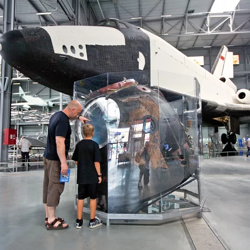 Ein Mann und ein Junge stehen vor einem Museumsobjekt im Technik Museum Speyer